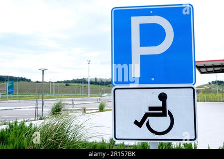 Primo piano cartello di parcheggio per disabili con area parcheggio. Area open space. Foto Stock