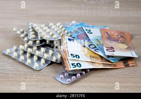 Immagine simbolica per il costo elevato della medicina con le pillole sul denaro Foto Stock