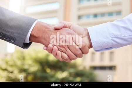 È sempre un piacere fare affari con voi. due uomini d'affari irriconoscibili che si levano in piedi fuori sul balcone insieme e scuotono le mani. Foto Stock