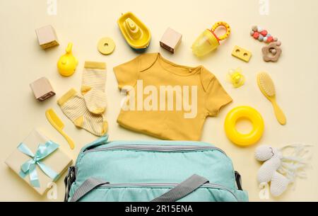 Composizione con abiti per bambini, giocattoli e accessori su sfondo giallo chiaro Foto Stock