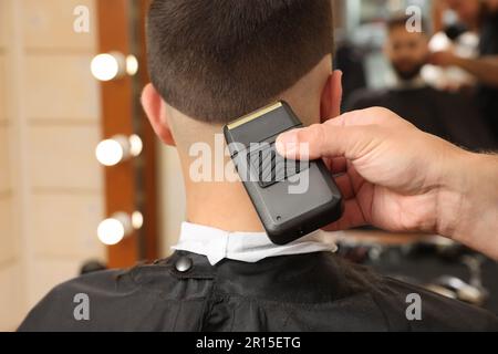 Parrucchiere professionale che lavora con il cliente in barbiere, guardaroba Foto Stock