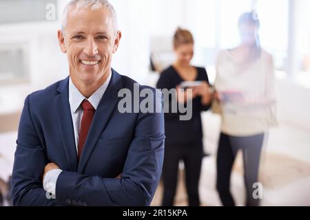 Il capo migliore del mondo. un uomo d'affari maturo con due colleghi che chiacchierano in background. Foto Stock