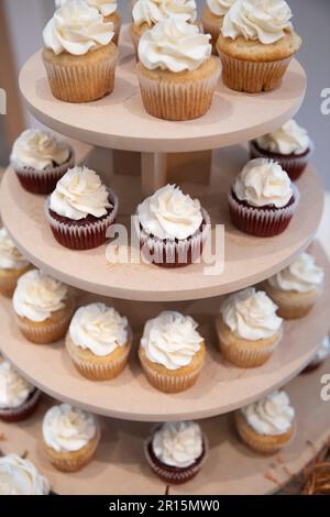 primo piano della torre dei cupcake di nozze con velluto rosso e vaniglia con glassa di crema bianca. dettagli del ricevimento nuziale Foto Stock