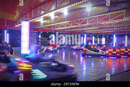 Auto paraurti in movimento ad un luna Park, divertimenti in Inghilterra, Regno Unito al crepuscolo Foto Stock