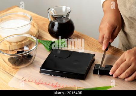 Donna mano tagliata a fette Cincau Hitam o Black Grass Jelly Pudding in pezzi Cube, sano concetto di cibo Foto Stock