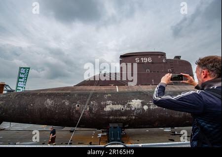 Nijmegen, Paesi Bassi. 11th maggio, 2023. Si vede un uomo scattando una foto del sottomarino ormeggiato al molo. Il sottomarino della Marina tedesca del U17 si caricò su un pontone galleggiante, navigando attraverso il paese passando e trascorrendo la notte a Nijmegen, al Waalkade. Con 500 tonnellate e una lunghezza di 50 metri e un'altezza di 9 metri, il sottomarino che partì da Kiel in aprile sarà poi assegnato un posto temporaneo di fronte al Museo della tecnica Speyer, in Germania. Credit: SOPA Images Limited/Alamy Live News Foto Stock