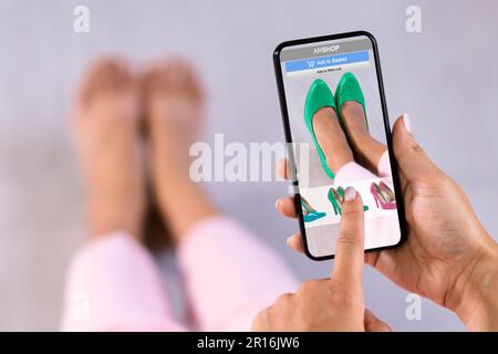 Donna che prova le scarpe con tacco alto virtuale in negozio o nell'app AR del negozio Foto Stock