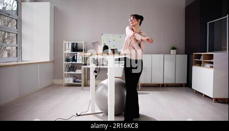 Donna che usa la scrivania regolabile in altezza in ufficio per una buona postura Foto Stock