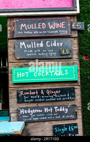 Un cartello per un bar pop-up al Mill Road Winter Fair pubblicizza VIN brulé, sidro brulé e cocktail caldi. Cambridge, Regno Unito Foto Stock