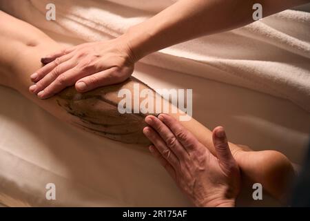 Massoterapista esperto che dà massaggio anticellulite alla cliente femminile Foto Stock