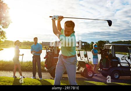 Giocare il suo miglior gioco di sempre. un uomo che gioca una partita di golf con i suoi amici. Foto Stock