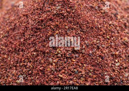 Primo piano sumac sfondo. Spezie in polvere di Sumac rosso macinato e secco. Concetto di spezie. Sfondo speziato. Foto Stock