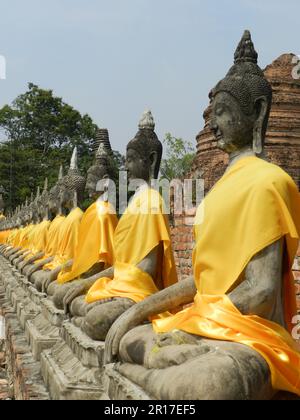 Thailandia, Ayuthaya (ex capitale reale 1350-1767): Fila di figure di Buddha ingarbuggiate in abiti di zafferano a Wat Yai Chai Mongkhon. Foto Stock