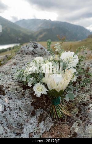 Il bouquet della sposa giace su una pietra Foto Stock