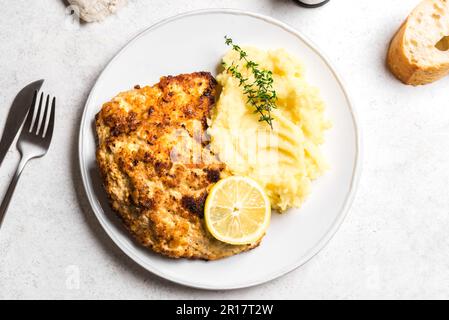 Schnitzel tedesco con purè di patate fresche, limone e timo primo piano. Trita di carne di maiale arrosto fatta in casa. Wiener Schnitzel. Foto Stock