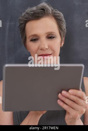 Come rendere i contatti in linea. Una donna d'affari matura che lavora sul suo tablet digitale. Foto Stock