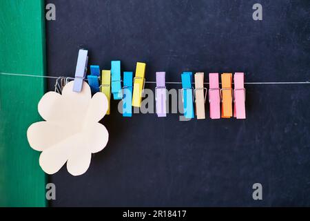 corda con clothespins colorati e adesivi vuoti per appunti su sfondo nero della schoolboard Foto Stock