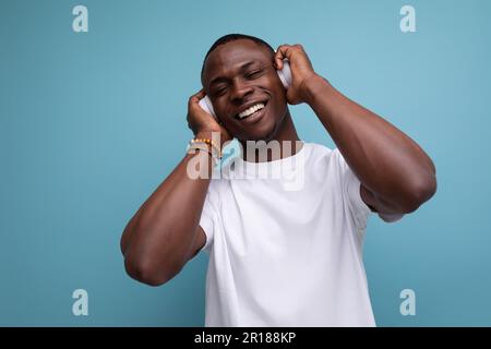 bel giovane ragazzo africano ben curato che balla con la musica in cuffie Foto Stock