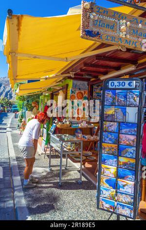 Kamari, Santorini, Grecia: Cartoline e souvenir in stand presso il lungomare del villaggio di Kamari fiancheggiato da graziose caffetterie e taverne tradizionali delle cicladi Foto Stock