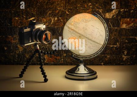 Una foto di una vecchia macchina fotografica che guarda al World Traveler Globe decorativo Foto Stock