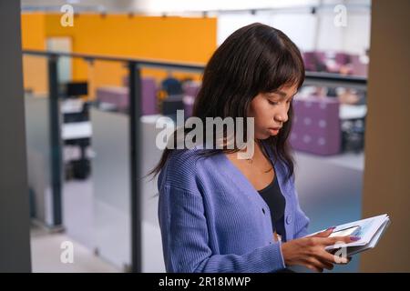 Donna seria in piedi su sfondo sfocato della camera moderna Foto Stock