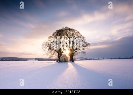 Una splendida scena invernale con un tramonto mozzafiato su un campo innevato Foto Stock