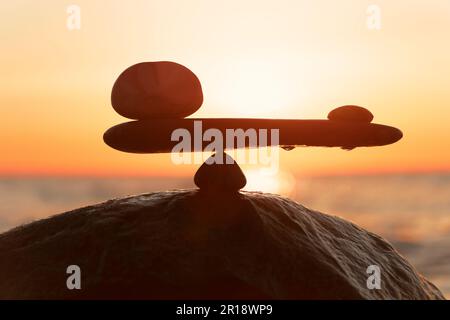 nell'equilibrio del potere - scale naturali di pietre dal mare al tramonto arancione - foto simbolo Foto Stock