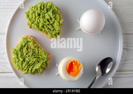 Colazione europea. Uovo sodo e panino aperto con avocado sul tavolo. Cibo tradizionale per una sana colazione. Foto Stock