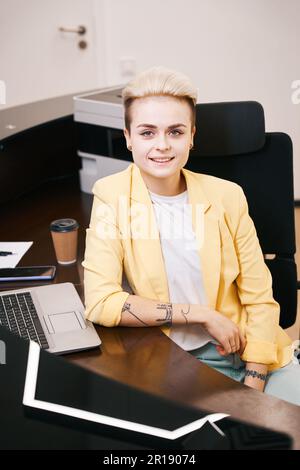 Capo giovane donna felice seduto sul posto di lavoro Foto Stock