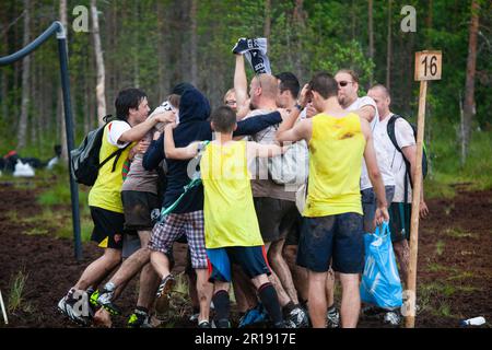 SWAMP SOCCER, FINLANDIA, 2014: I giocatori celebrano il successo della loro squadra. L'annuale Swamp Soccer World Championship 2014 a Ukkohalla a Hyrnsalmi, Finlandia. Fotografia: Rob Watkins. INFO: Swamp Soccer è un fenomeno sportivo bizzarro e fangoso. Giocata su terreni boggy, questo adattamento del calcio aggiunge un tocco di divertimento. I partecipanti si divertono nel caos, trasformando uno sport tradizionale in un'esperienza divertente e memorabile che attira sia giocatori che spettatori. Foto Stock