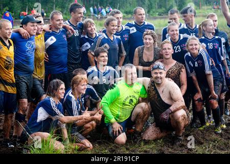 SWAMP SOCCER, FINLANDIA, 2014: I giocatori celebrano il successo della loro squadra. L'annuale Swamp Soccer World Championship 2014 a Ukkohalla a Hyrnsalmi, Finlandia. Fotografia: Rob Watkins. INFO: Swamp Soccer è un fenomeno sportivo bizzarro e fangoso. Giocata su terreni boggy, questo adattamento del calcio aggiunge un tocco di divertimento. I partecipanti si divertono nel caos, trasformando uno sport tradizionale in un'esperienza divertente e memorabile che attira sia giocatori che spettatori. Foto Stock