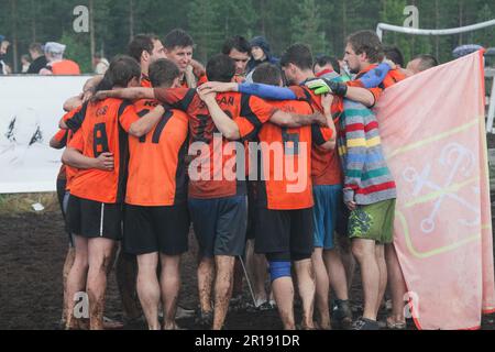 SWAMP SOCCER, FINLANDIA, 2014: I giocatori celebrano il successo della loro squadra. L'annuale Swamp Soccer World Championship 2014 a Ukkohalla a Hyrnsalmi, Finlandia. Fotografia: Rob Watkins. INFO: Swamp Soccer è un fenomeno sportivo bizzarro e fangoso. Giocata su terreni boggy, questo adattamento del calcio aggiunge un tocco di divertimento. I partecipanti si divertono nel caos, trasformando uno sport tradizionale in un'esperienza divertente e memorabile che attira sia giocatori che spettatori. Foto Stock