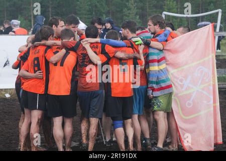 SWAMP SOCCER, FINLANDIA, 2014: I giocatori celebrano il successo della loro squadra. L'annuale Swamp Soccer World Championship 2014 a Ukkohalla a Hyrnsalmi, Finlandia. Fotografia: Rob Watkins. INFO: Swamp Soccer è un fenomeno sportivo bizzarro e fangoso. Giocata su terreni boggy, questo adattamento del calcio aggiunge un tocco di divertimento. I partecipanti si divertono nel caos, trasformando uno sport tradizionale in un'esperienza divertente e memorabile che attira sia giocatori che spettatori. Foto Stock