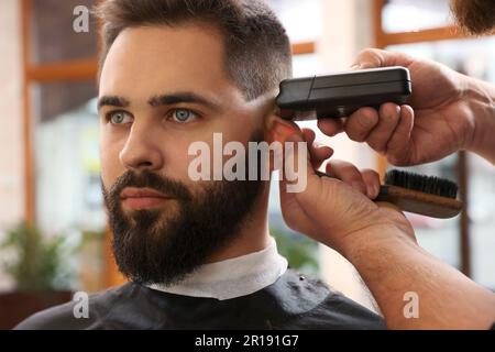 Parrucchiere professionale che lavora con il cliente in barbiere, guardaroba Foto Stock