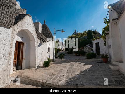 ALBEROBELLO, ITALIA - 29 OTTOBRE 2021: Case bianche Trulli ad Alberobello, Italia nel bel pomeriggio di sole con effetto flare lente Foto Stock