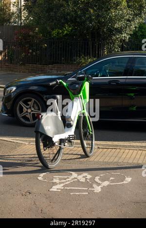 Noleggio Lime noleggio biciclette e bike / bici elettriche e male parcheggiato da un ciclista sulla pista ciclabile marciapiede di una strada / strada a Twickenham, Regno Unito. (134) Foto Stock