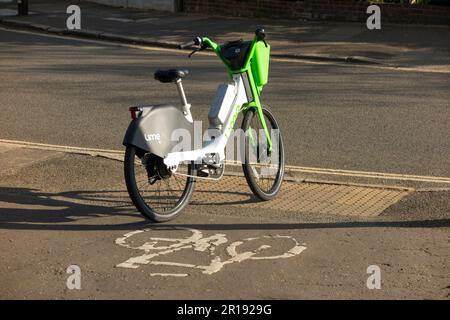 Noleggio Lime noleggio biciclette e bike / bici elettriche e male parcheggiato da un ciclista sulla pista ciclabile marciapiede di una strada / strada a Twickenham, Regno Unito. (134) Foto Stock