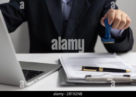 Uomo che timbrava un documento. Approvazione di documenti di lavoro, finanza, banca o marketing di investimento sulla scrivania. Foto Stock