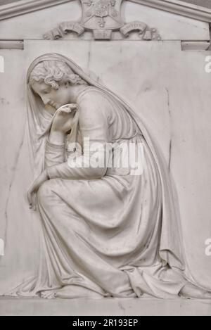 Scultura in rilievo in marmo in una chiesa di donna che prega in posizione di inginocchiamento. Foto Stock