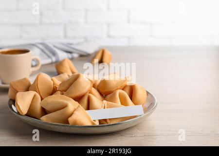 Gustosi biscotti e carta fortuna con predizione su tavolo di legno, spazio per il testo Foto Stock