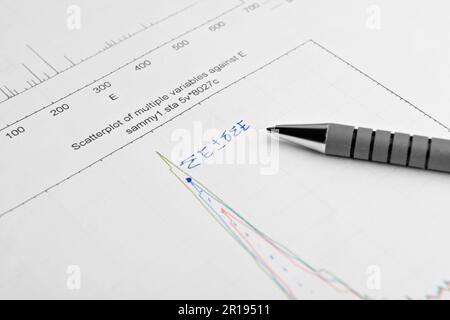 Carta con grafico a dispersione stampato, calcoli matematici scritti e penna, primo piano Foto Stock