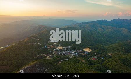 Veduta aerea sulla cima del tramonto il villaggio lontano dalla civiltà viaggiando su una strada difficile. Splendida vista del tramonto sul complesso collinare. Le Foto Stock