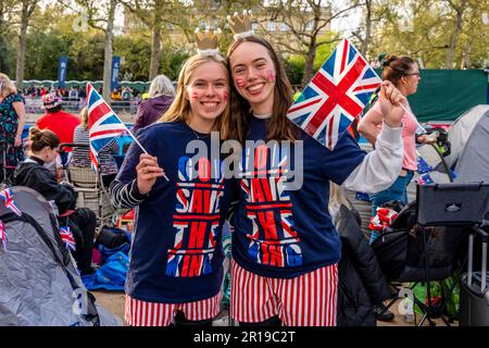 I giovani ondano le bandiere dell'Unione sul Mall prima dell'incoronazione del re Charles III, Londra, Regno Unito. Foto Stock