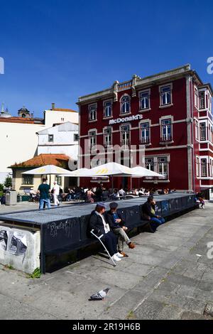 Persone sedute nella piazza di fronte al fast food McDonald's in Rua da Reboleira, quartiere Ribeira, Porto / Porto, Portogallo Foto Stock