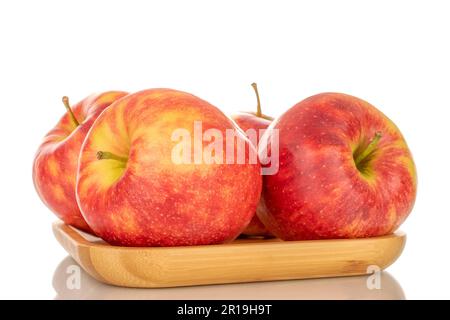 Quattro mele rosse mature su un vassoio di bambù, macro, isolate su fondo bianco. Foto Stock