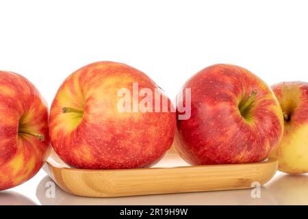 Quattro mele rosse mature su un vassoio di bambù, macro, isolate su fondo bianco. Foto Stock