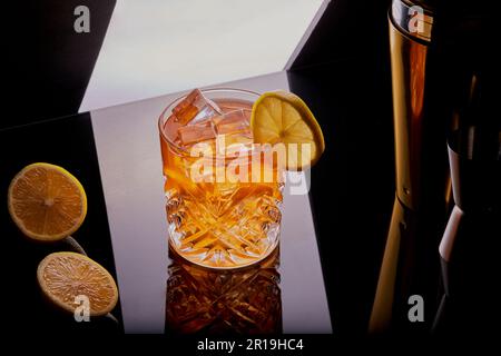 cocktail whisky guarnito con una fetta di limone appoggiata su una superficie del bar. Foto Stock