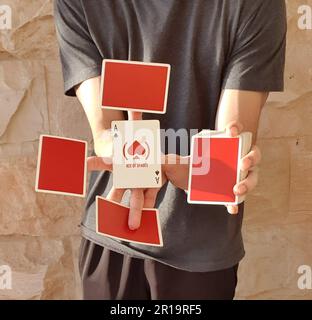 Un giovane che esegue un trucco di carta con un mazzo di carte rosse da gioco. Foto Stock