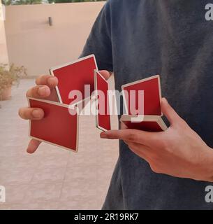 Un giovane che esegue un trucco di carta con un mazzo di carte rosse da gioco. Foto Stock