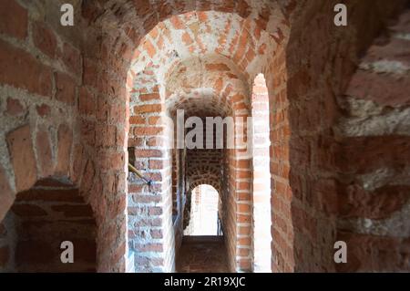 Stretti vecchi corridoi del castello, gallerie, archi di mattoni rossi in un castello medievale. Foto Stock